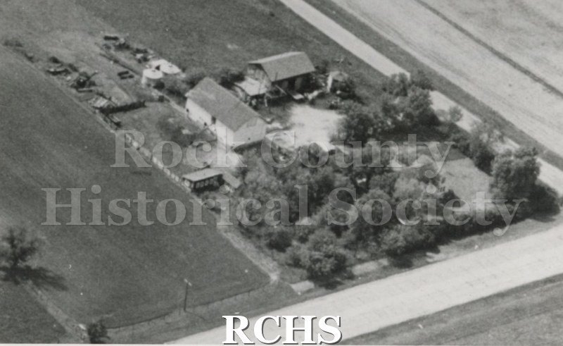 Black and white aerial photograph of the Yasaitis Farm. Shown are the house, barn, and many trees on the right.