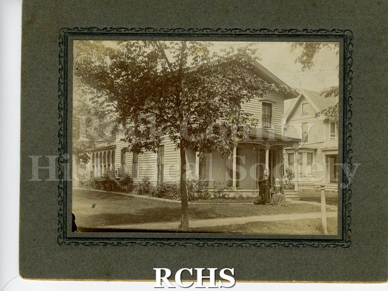 Black and white photograph of 156 (now 162) Cherry St. Shows a house with two people, one standing and one sitting.