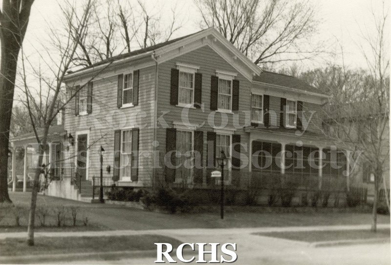 Black and white photograph of a two story house with a screened in porch on the front at 220 S. Academy.