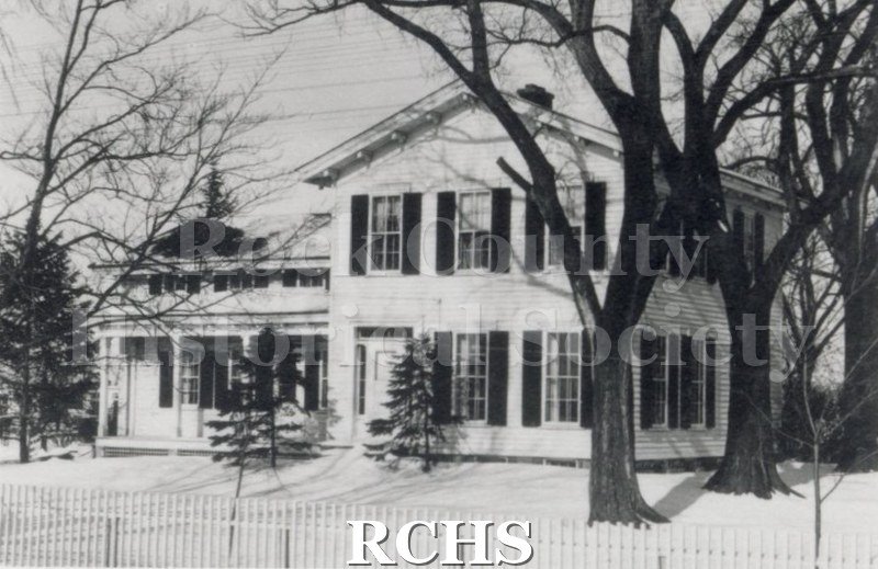 Black and white photograph of the Green-Roberts House, a two story house with a one story addition on the left and a fence in front.
