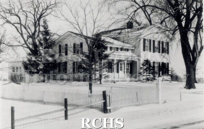 Black and white photograph of the Green-Roberts House, a two story house with a one story addition on the left and a fence in front. There is snow on the ground.