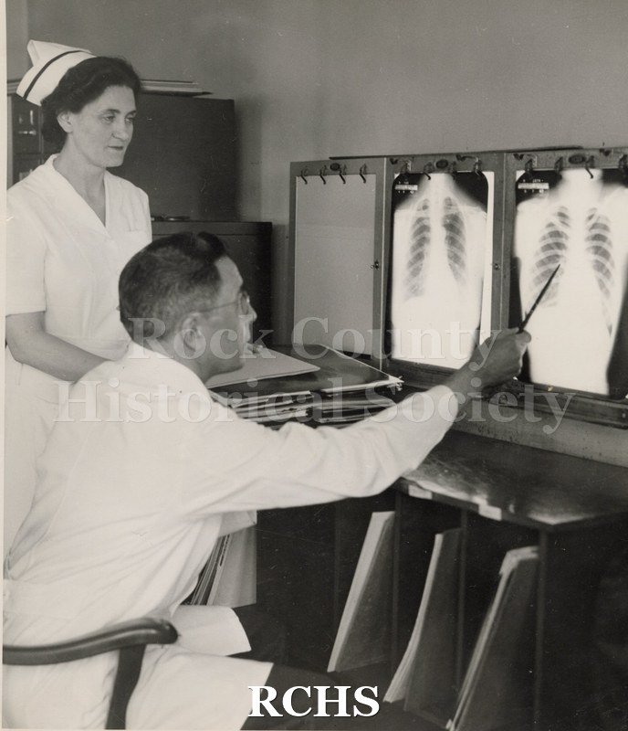 Black and white photograph of Miss Murphy and Dr. E. K. Steinkopf looking at lung x-rays.