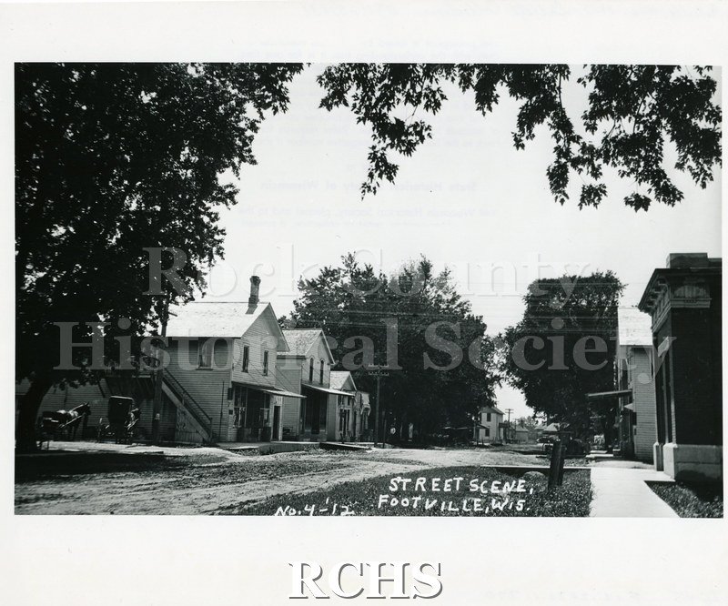 Historic image of Black and white copy print of a street in Footville, Wisconsin. On bottom: "Street Scene Footville, Wis. No.-4-'12".