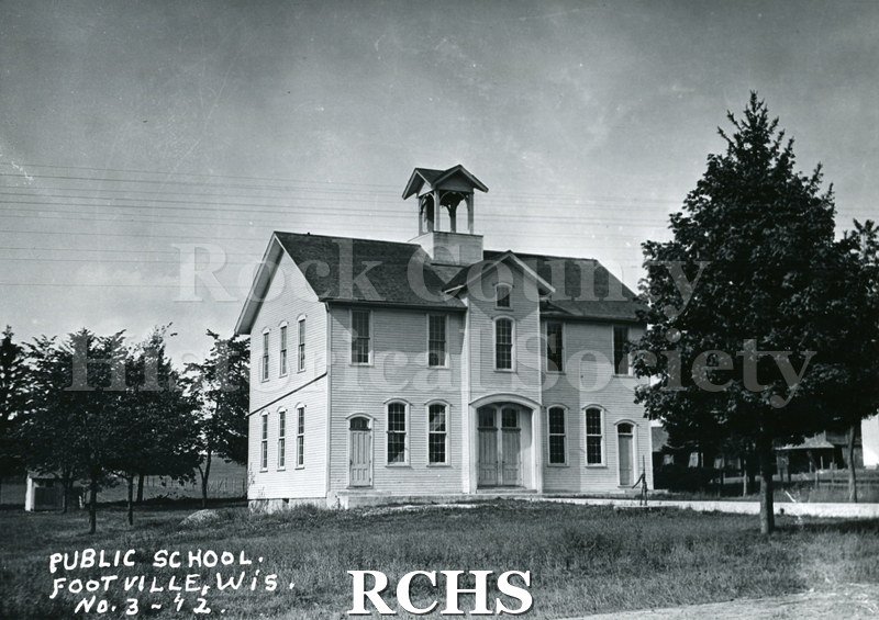 Historic image of Black and white copy print of a two story school with a bell on top. On bottom: "Public School Footville, Wis. #3-/12.