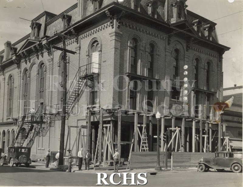 Black and white photograph of the exterior of a building on the corner of Main and Court Street being remodeled.