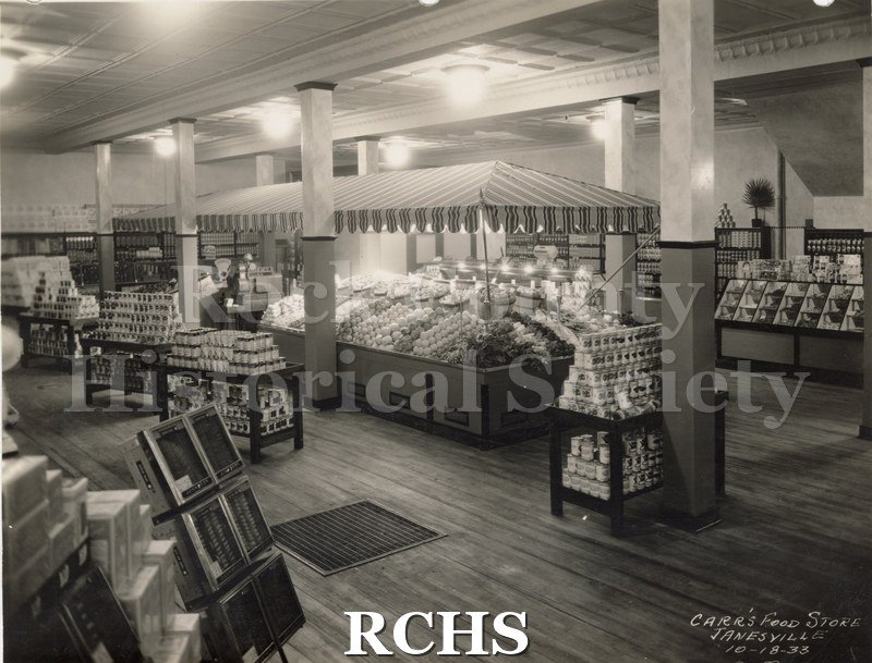 Black and white photograph of the interior of Carr's Grocery Store showing displays of canned goods and fruits.
