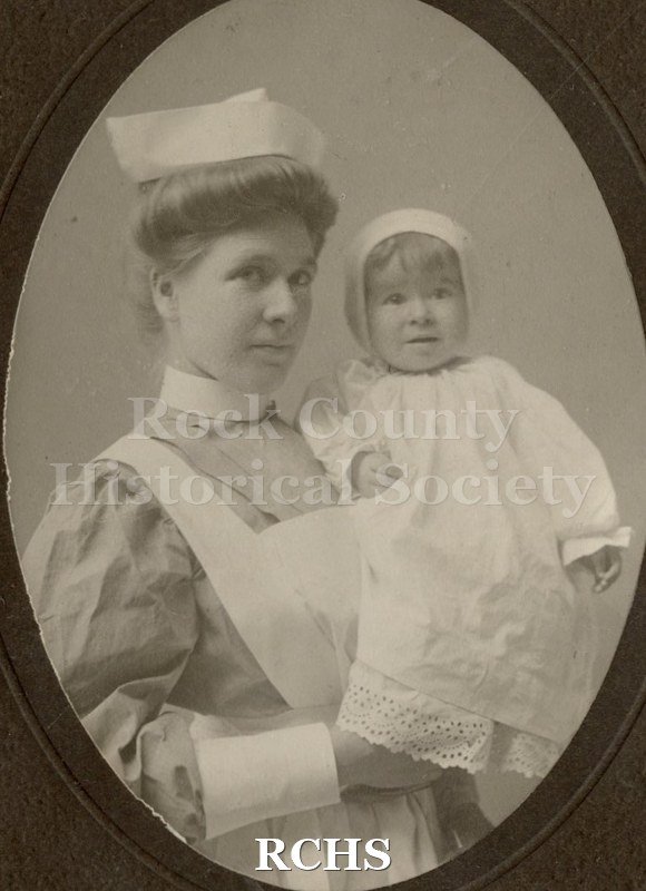 Black and white photograph of Minnie Tews, a nurse, holding a baby.