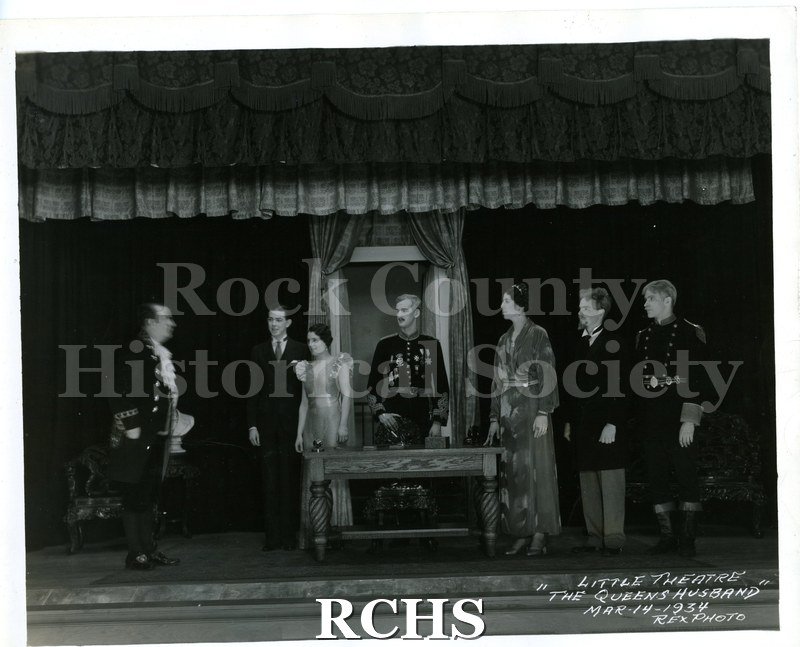 Black and white photograph of a scene from Janesville Little Theatre's production of "The Queen's Husband." Notation on lower right corner of photo: "LITTLE THEATRE.