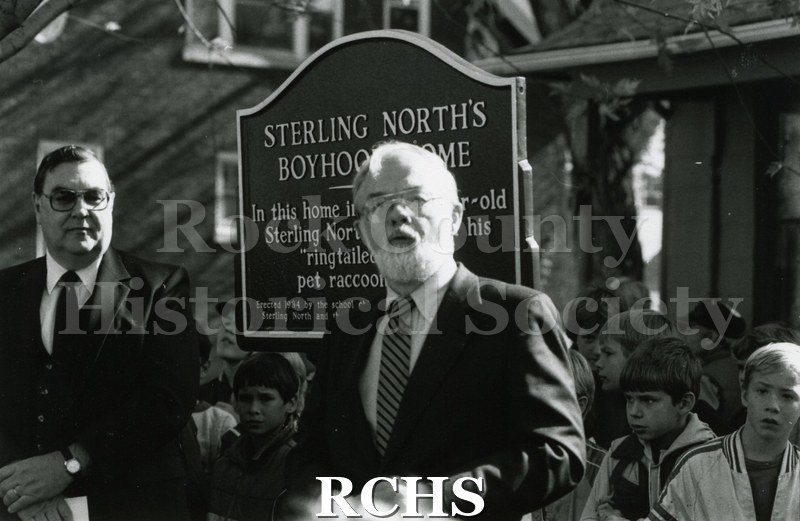 Black and white photograph of the dedication of Sterling North boyhood home. Shows a man standing in front of the marker for Sterling North's Boyhood Home.