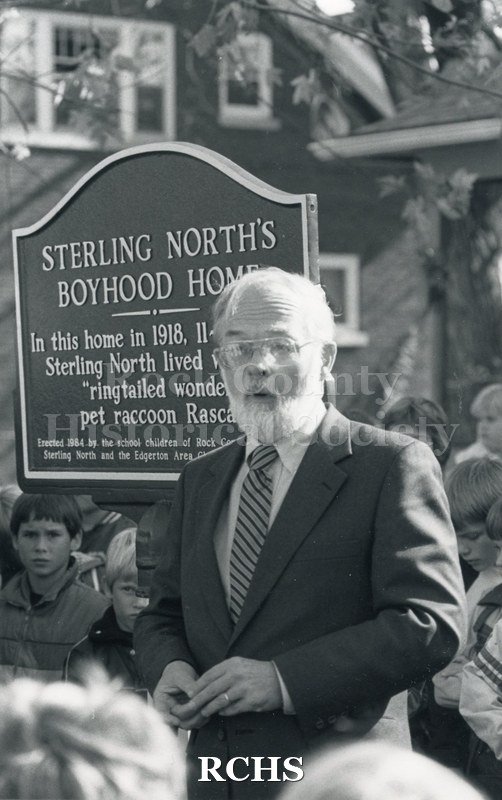 Black and white photograph of the dedication of Sterling North boyhood home. David Sterling North is standing in front of a marker addressing a crowd.