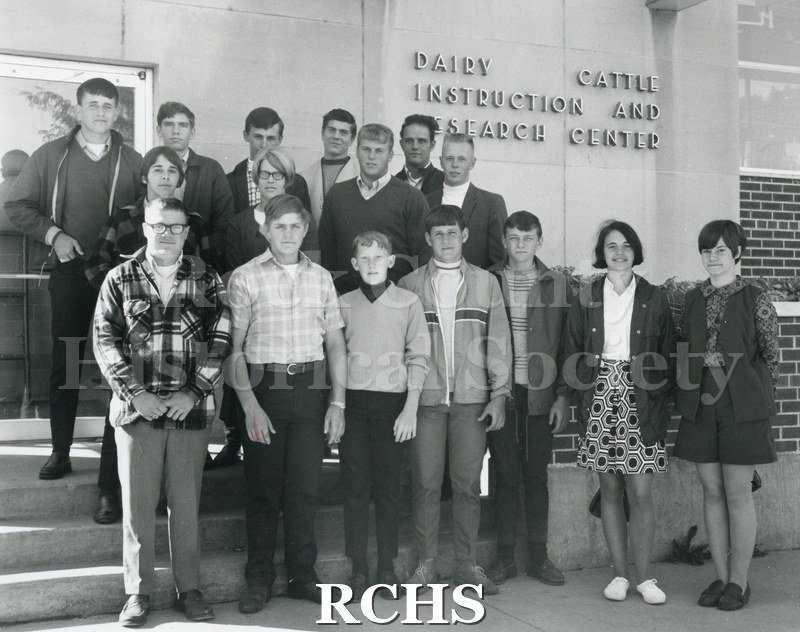 SBlack and white photograph of sixteen young people standing near a building with "Dairy Cattle Instruction and Research Center" on the wall.