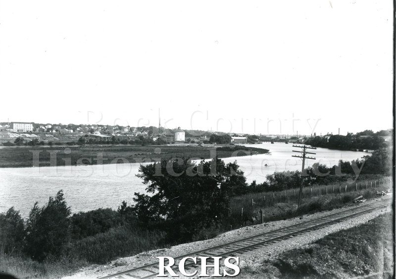 Black and white copy print of a view of Rock River with railroad tracks in front.