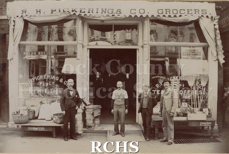 Black and white photograph of R. H. Pickering & Co. Grocery store. There are four men standing in front of the store.