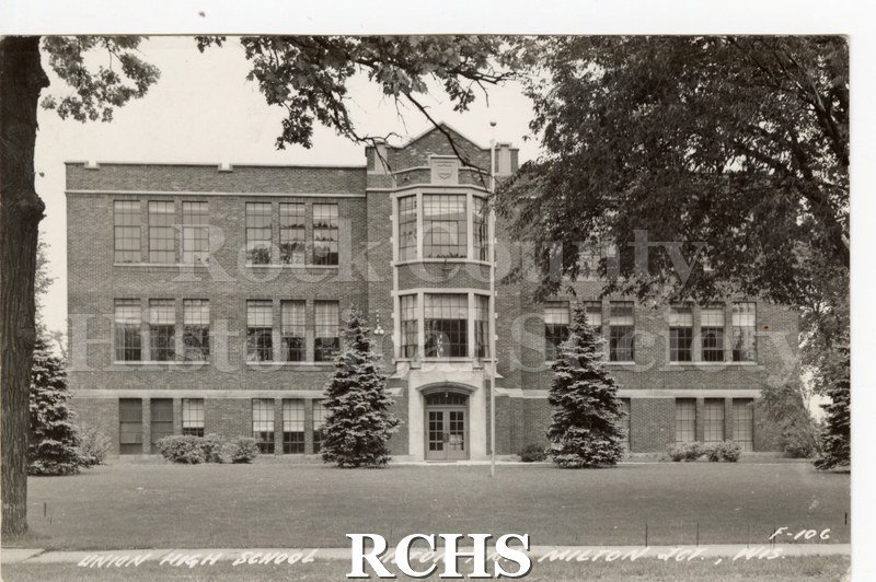 Postcard. Photograph of Union High School. Brick building, tower in center, two evergreen trees in front.