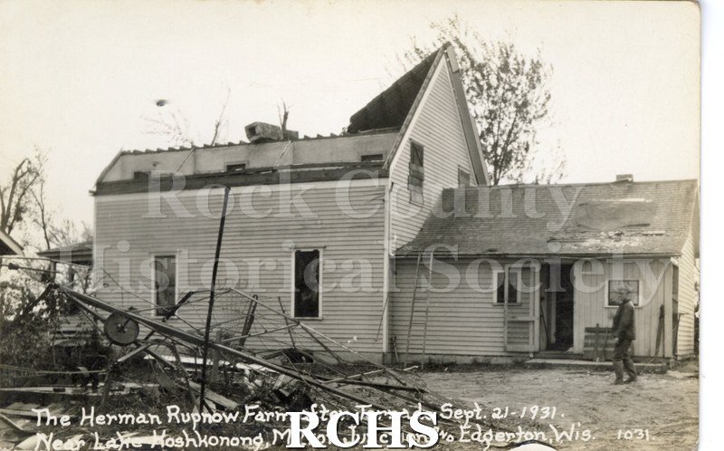 3-1/2" x 5-1/2" glossy picture postcard showing remains of farmhouse after tornado. There is a man standing by the house.