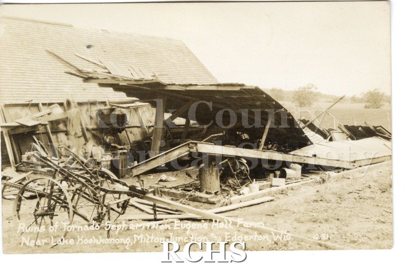 3-1/2" x 5-1/2" glossy picture postcard showing a collapsed building with a farm machine in front of it. On bottom: "Ruins of Tornado Sept.