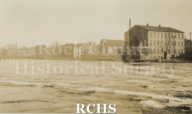 Historic image of Rock River at flood stage. Buildings are visible in the background..