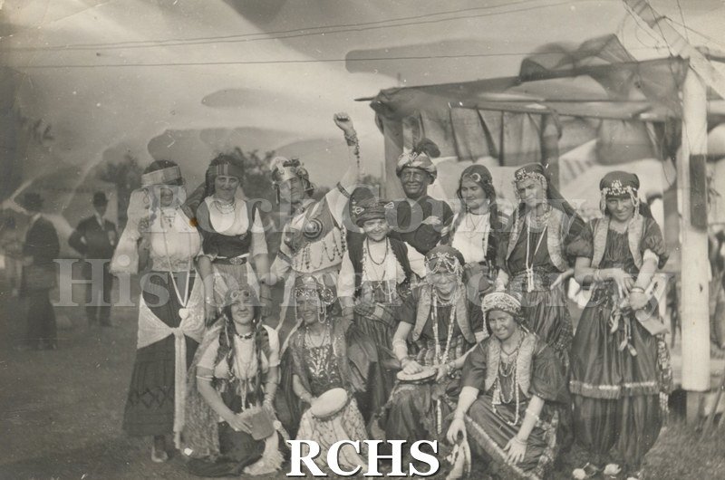 Black and white photograph of Carnival performers. Shows a group of people in costume.