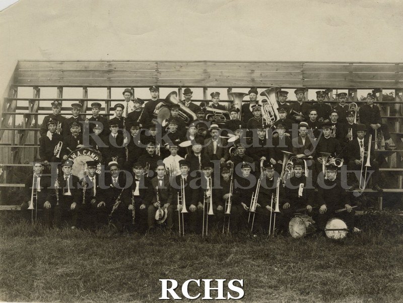 Black and white photograph of musicians at Musician's Picnic 1909 at Yost's Park are posed on risers wearing uniforms and holding instruments.
