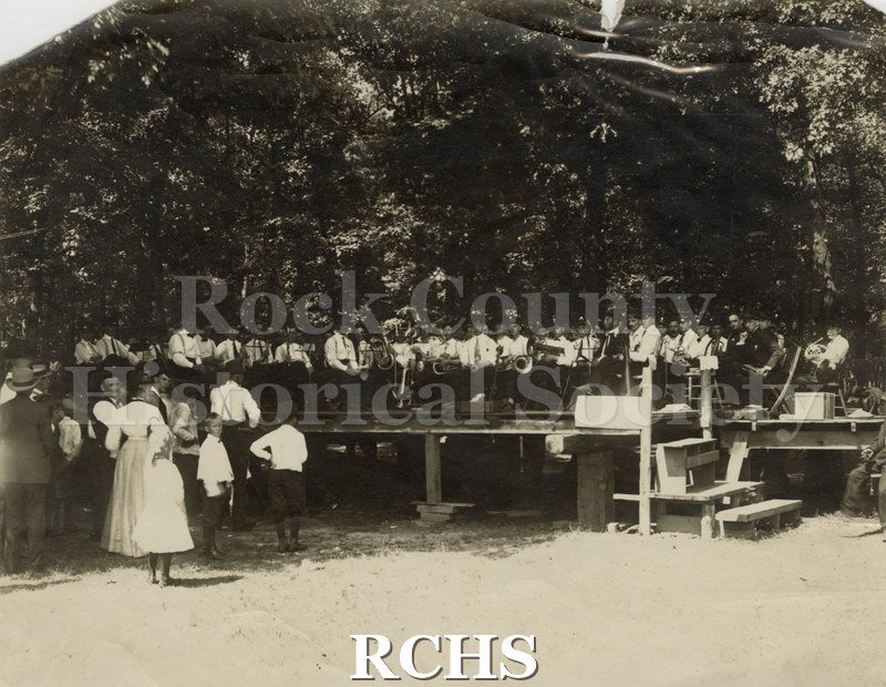 Historic image of Musicians at Musician's Picnic 1909 at Yost's Parkare shown on a stage wearing uniforms and holding instruments.