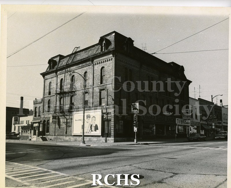 Black and white photograph of the Carle Block. Shows a two story building at an intersection of two streets.
