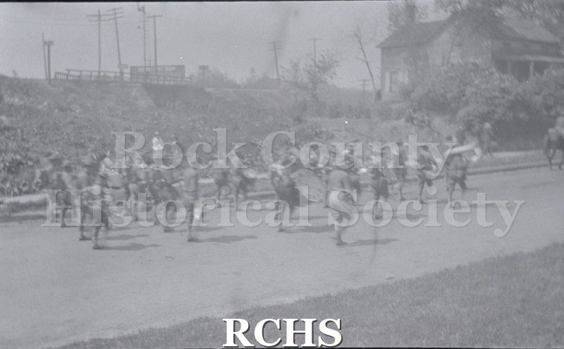 Black and white photograph of WWI soldier marching band walking down a street. Armistice Day Parade 11/11/1917, Janesville Wi Scanned from negative.