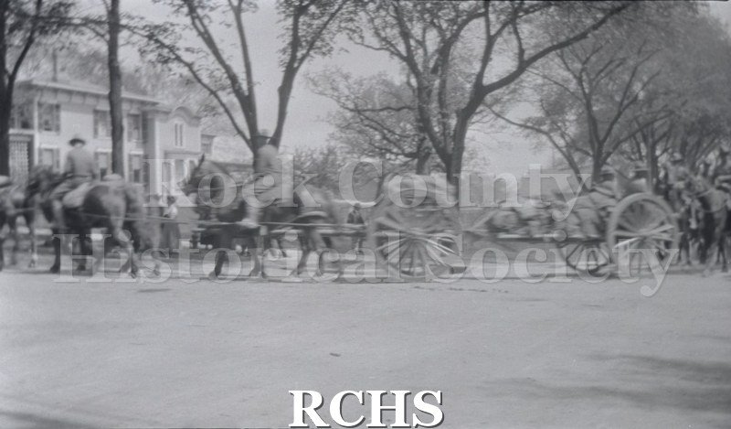 Black and white photograph of horses pulling a caisson along a street. Armistice Day Parade 11/11/1917, Janesville Wi Scanned from negative.