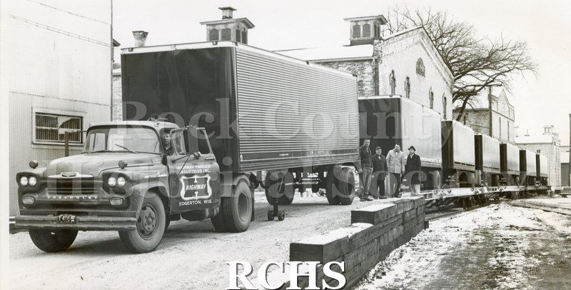 Grayscale. Image depicts a line of large trucks on a snowy road. On the first truck's door: "Highway Trailer Industries Inc. Edgerton, Wis." Chevrolet trucks.