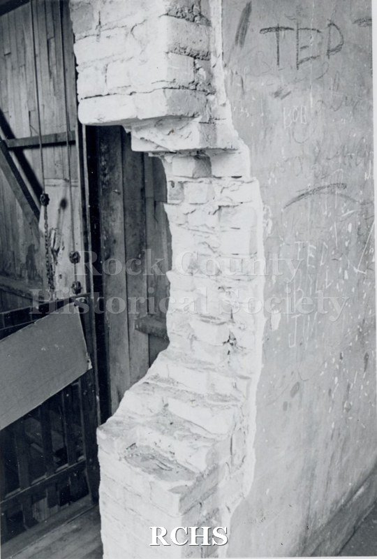 Black and white photograph of Myers Block-Old Armory, Janesville, WI, interior view, showing bricks and a section of a wooden structure.